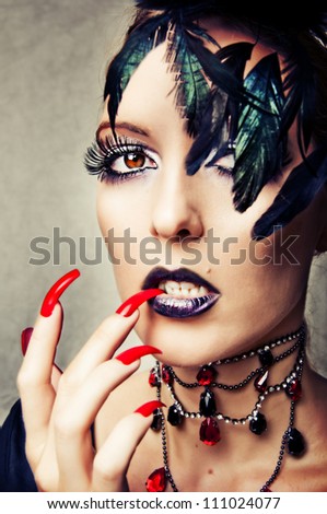Fashion portrait of sexy female vampire with gothic make up and long red nails