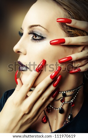 Woman face with fashion make up, false lashes and long red finger nails