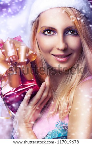 Christmas concept. Beauty portrait happy woman model holding gift in hands and smile in santa claus hat and with bright make-up