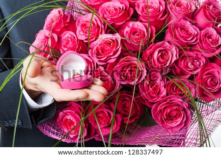 Man with flowers and ring in pink box. Proposal scene or Valentines day.