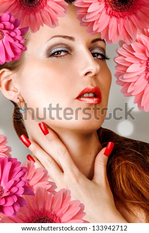 Young woman with long false lashes, fashion red nails and sensual lips with flowers