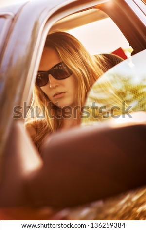 Beautiful young sexy woman wearing sun glasses  in car looking from window on nature background