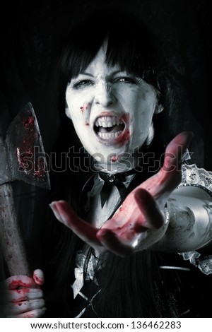 Dead female zombie with bloody axe extends hand to shot. Halloween concept
