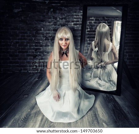 Young Beautiful Blond Woman Sitting On Wooden Floor In Old Dark Room With Big Knife In Mirror Reflection