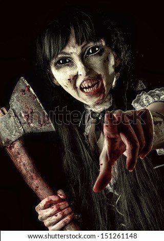 Dead female zombie with bloody axe extends hand to shot. Halloween concept. Evil ghost pointing at you