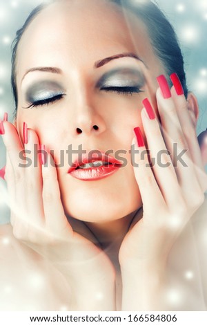 Winter Skin Care. Beautiful female face with red lips and long lashes. Long false nails