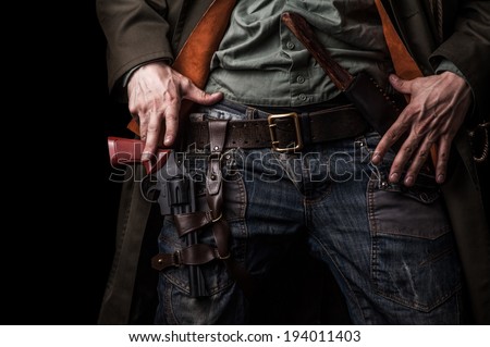 Male hands cowboy and a revolver on his belt on black background