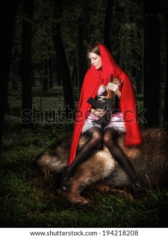 Little Girl Red Riding Hood with automatic in wood sit on killed wolf