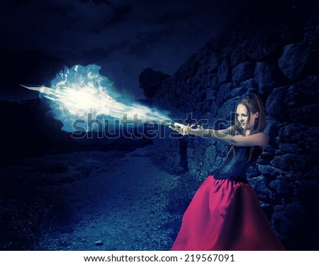 beautiful woman witch trains in medieval castle cast magic - blue cold ball of ice from hands