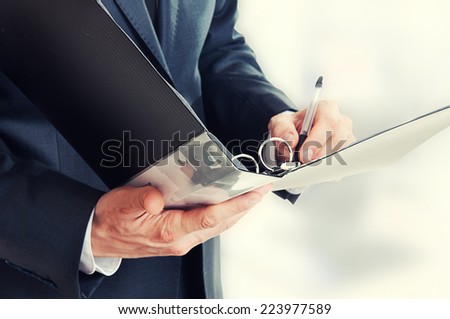 Folder for documents closeup in focus. Businessman writing in office -  his hand  signing contract.