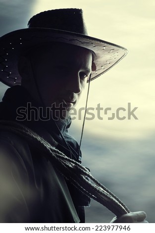 silhouette of Handsome man in cowboy costume stay in steppe at night with full moon. Vampire Hunter