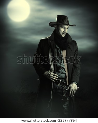 Handsome man in cowboy costume stay in steppe at night with full moon. Vampire Hunter