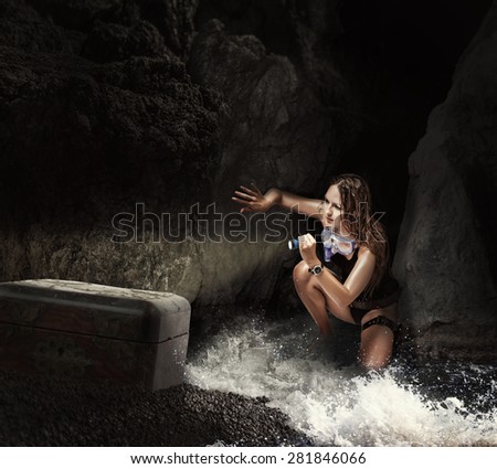 Adventure. Woman traveler and explorer in sea cave, shining a flashlight into the chest searching treasures