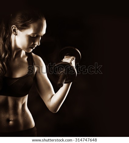 Dark sepia contrast photo of fitness woman with muscular belly and arms training with dumbbells in studio, on black background and copy space