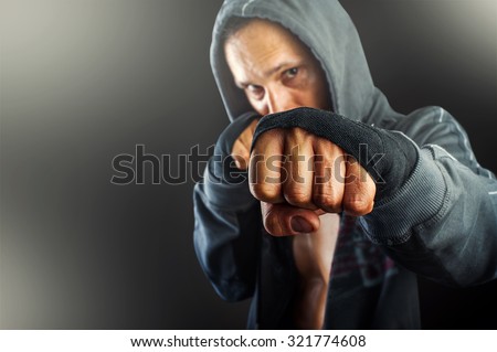 fist of young dangerous man closeup. strong serious  athletic man wearing hoodie shirts standing in boxing pose