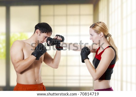 Couple fight. Young adult cute woman fighter punching man, studio shot