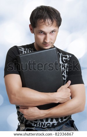 Portrait of young handsome man on blur blue background. He holding laptop computer