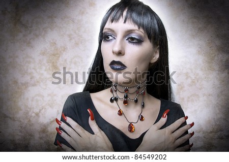 Halloween concept. Fashion portrait of gothic style woman night vampire or evil witch in black dress and vintage necklace. Brunette with long health hair.