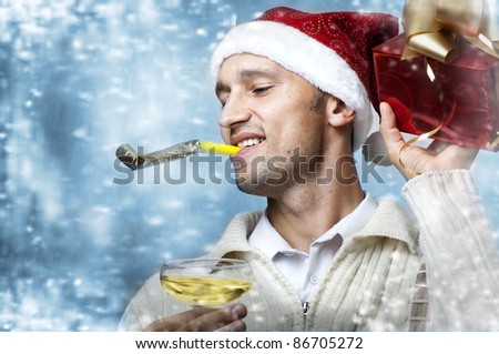Christmas party. Young adult smiling caucasian handsome man in santa claus hat with christmas gift box and glass of champagne. Snow flakes