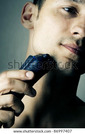 Fashion portrait of male chin and electric shaver. Focus on shaver