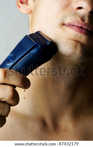 Fashion portrait of male chin and electric shaver. Focus on shaver