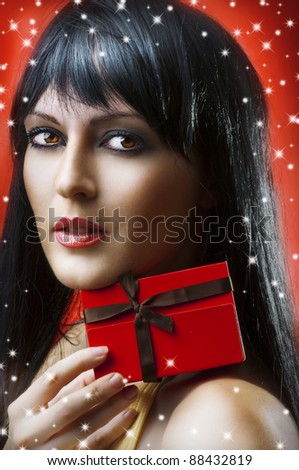 Glamour portrait of beauty woman with little red christmas gift box with brown ribbon on red background