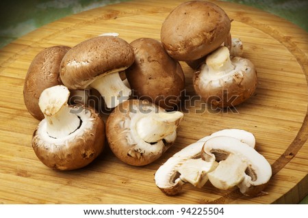 Champignon mushrooms with brown variety on wooden table and board