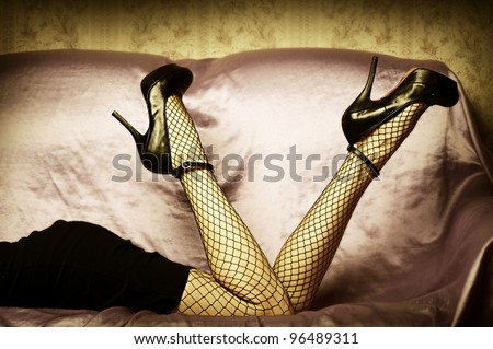 Sexy female legs in high heel black shoes and fishnet stockings. Retro style