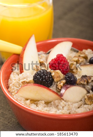 Bowl of delicious steel cut oats with fresh fruit, honey and orange juice