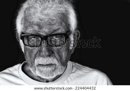 Black and white portrait of an elderly sad man with a tear rolling down his cheek