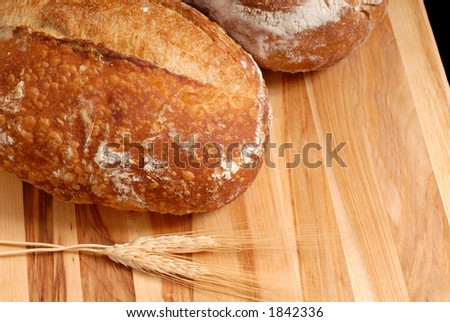 Italian bread loaves with wheat on cutting board