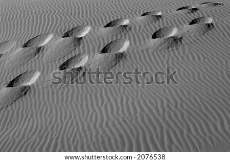Black and white image of footsteps in the sand dunes