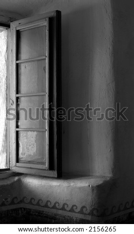 Black and white image of warm light washing through an open window in the Mission of Santa Barbara