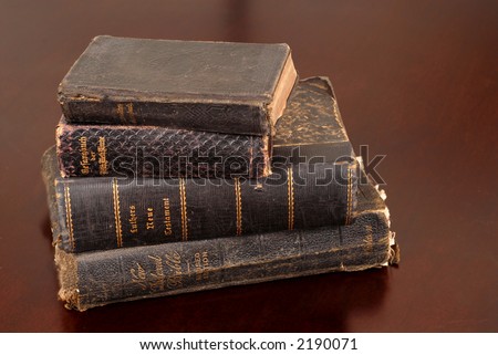 Stack of old bibles including German bibles resting on a table awash in warm light