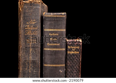 Three very old bibles including two German bibles standing on a table awash in warm light