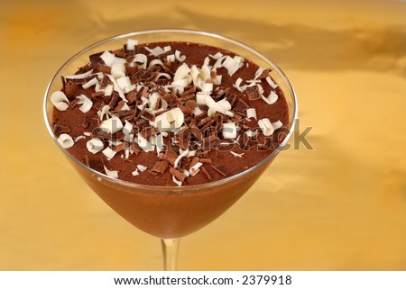 Chocolate pudding with chocolate curls in a martini glass on a gold background