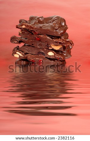 Chocolate cashew and dried cherry bark in water on a red background vertical view