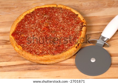 Chicago style deep dish pizza on a cutting board with cutter