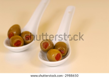 Stuffed green olives in two white spoons