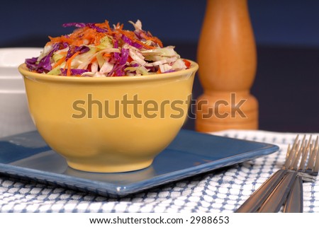 Crisp cole slaw in a yellow bowl resting on a blue plate