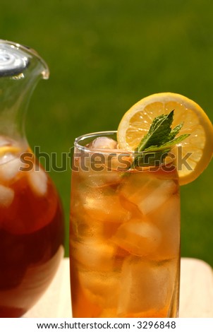 A glass of iced tea with a pitcher of tea alongside
