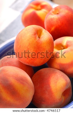 Several ripe peaches in a white and blue bowl