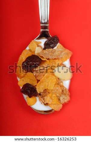 Spoonful of breakfast cereal flakes with almonds and dried cherries