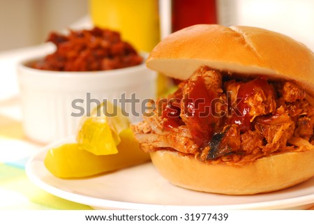 Barbecue pulled pork sandwich with baked beans and pickles