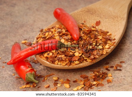 Hot red chili peppers and red pepper flakes on a wooden spoon