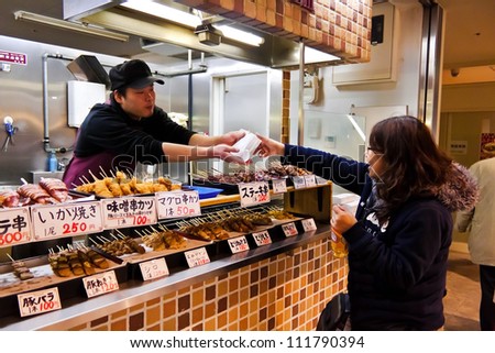 KANAZAWA, JAPAN - MARCH 28 : Unidentified Japanese shopkeeper hands a food package to an unidentified customer at the Omicho Market on March 28, 2012 in Kanazawa, Japan.