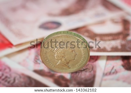 British pound coin placed on British pound banknotes