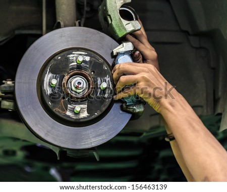 Hands of a mechanic install brake lining onto a car disc brake