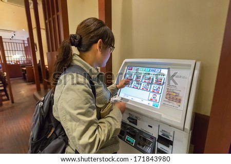 OKAYAMA, JAPAN - NOVEMBER 17: Food Vending Machine in Okayama, Japan on November 17, 2013. Unidentified female chooses her meal from a vending machine in a Japanese restaurant
