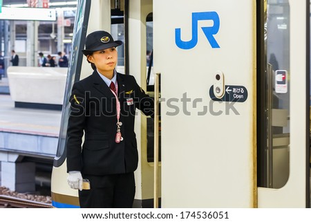 KOBE, JAPAN - NOVEMBER 17: Train conductor in Kobe, Japan on November 17, 2013. Unidentified train conductor observes for passengers before moving the train
